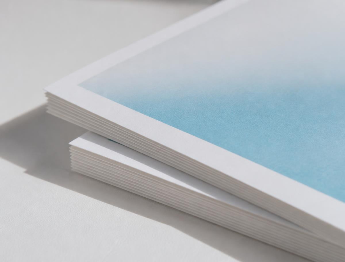 Stapel Fotopapier mit cyanfarbenem Farbverlauf im Tageslicht